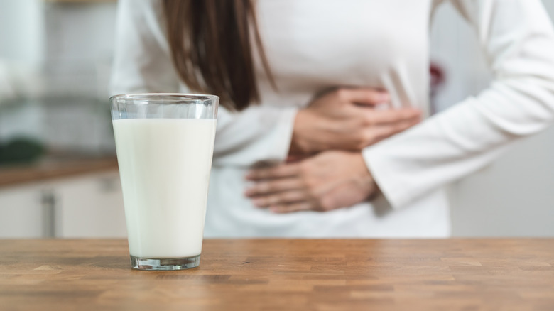 Glass of milk in front of person holding stomach