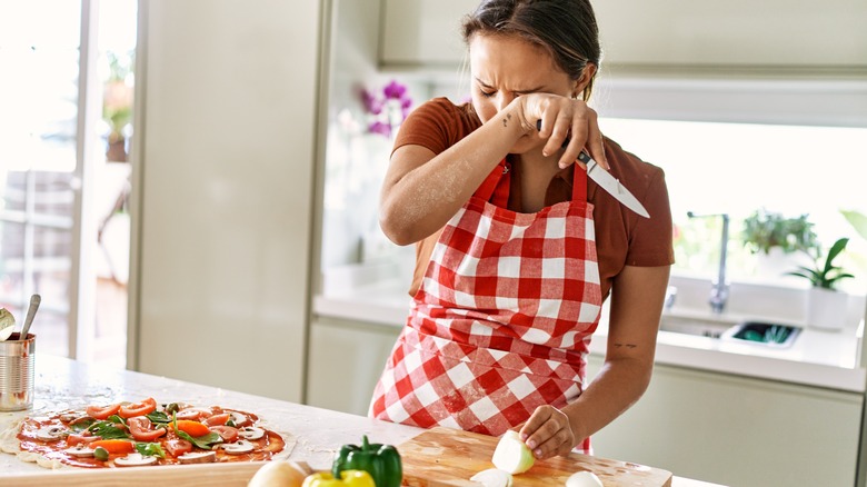 Woman crying while cutting onions