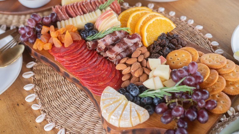 Charcuterie board with crackers, nuts, fruit