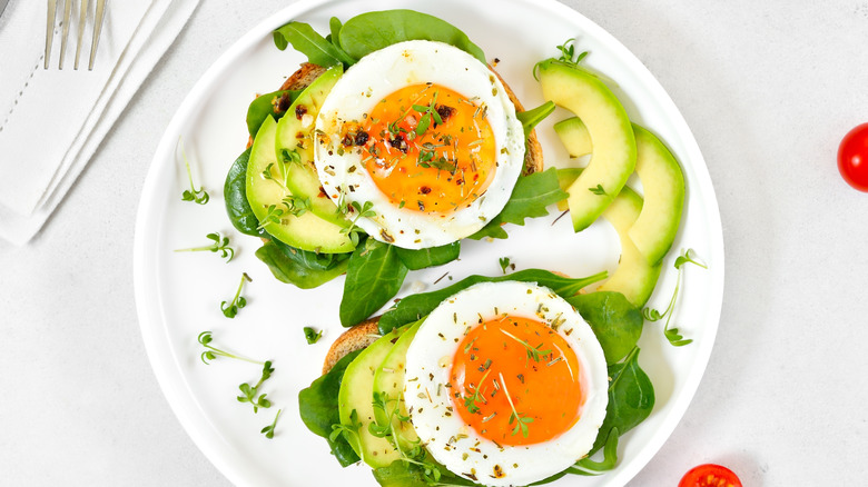 Fried eggs over sliced avocado