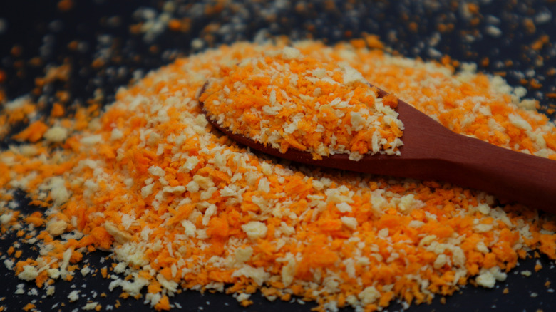 A pile of breadcrumbs with a wooden spoon