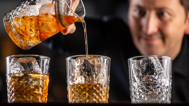 Person pouring cocktails into glasses