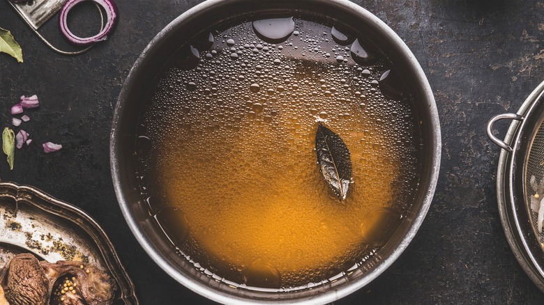 Top-down view of stockpot with broth on dark surface