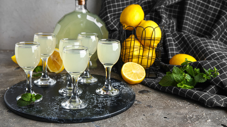 Six glasses of limoncello with lemons and a bottle