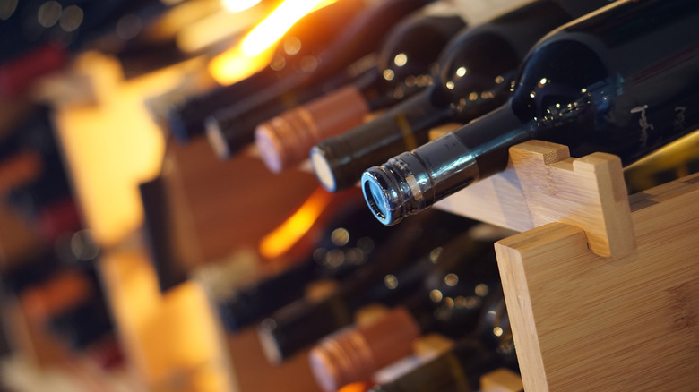 Wine bottles rest on their sides on wooden racks.