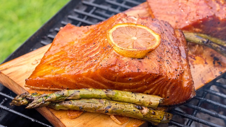 Salmon grilling on cedar plank with lemon slice on top