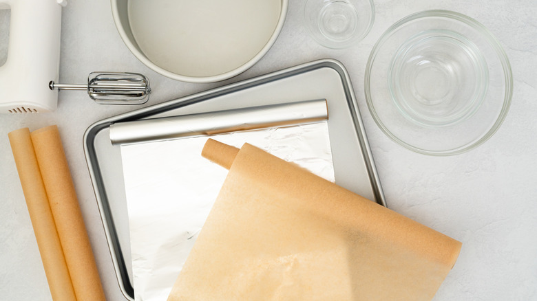 Parchment paper on top of aluminum foil, mixing bowls and baking pans beside electric mixer