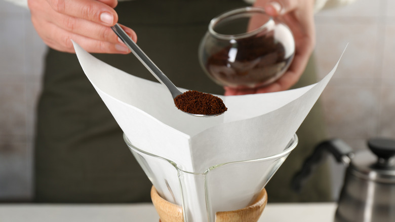 Person scooping coffee into top of coffee maker