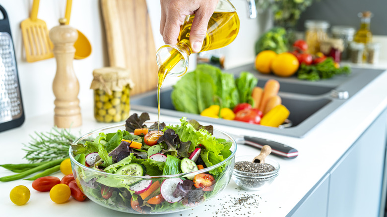 Person pouring dressing on a salad