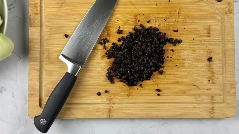 fermented black beans on a wooden board with a knife