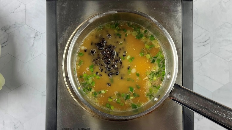 beans and onions in a pot of yellow liquid