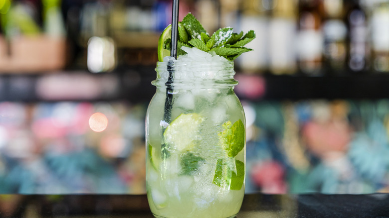 A mojito with ice, limes, and mint sprigs