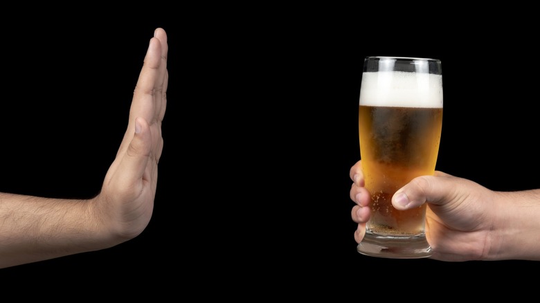 Person holding up hand to glass of beer