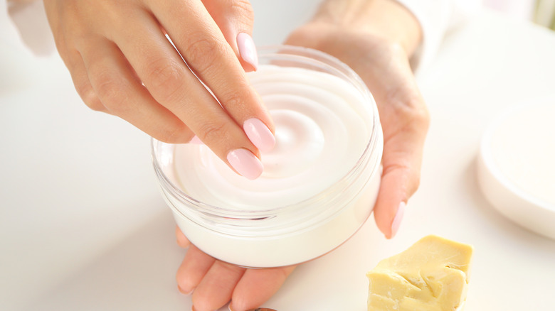 woman holding a jar of cocoa butter