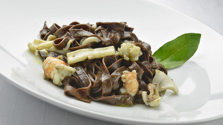 Pasta Dish Chocolate fettuccine with prawns and cuttlefish on a white plate