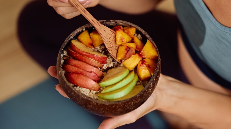 Close up of a woman eating a bowl of fruit salad