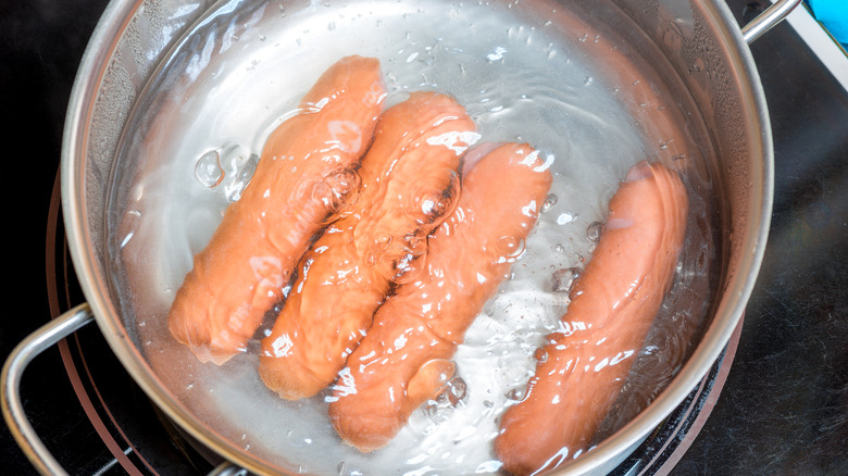 Opened hot dogs in simmering water