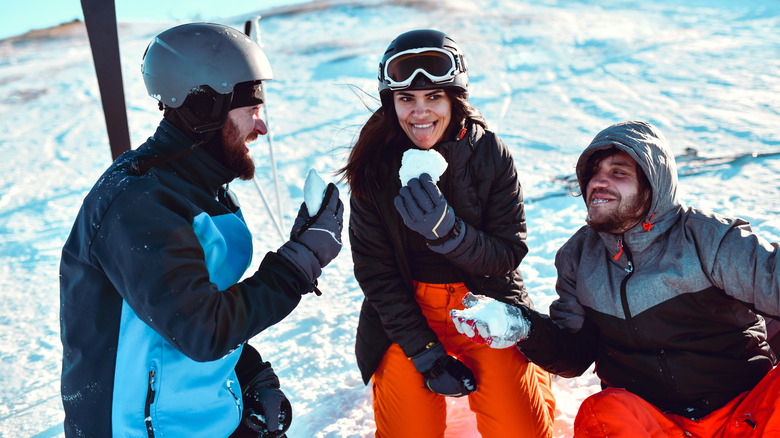 Three friends eating snow on ski slopes