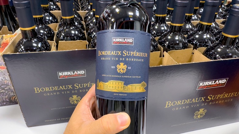 hand holding kirkland signature wine bottle