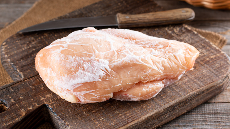Frozen chicken breast on wood board