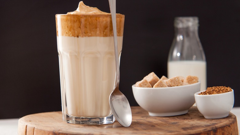 Dalgona coffee in glass near instant coffee and sugar cubes