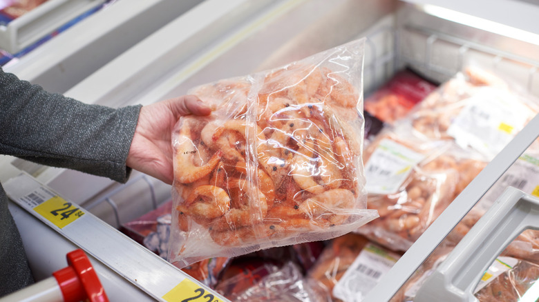 A woman holds a bag of frozen shrimp