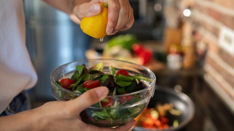 Person squeezing lemon into salad