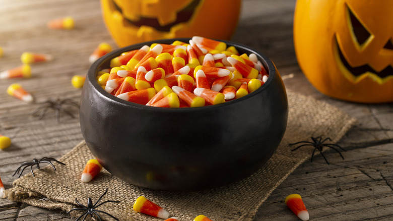 black bowl filled with candy corn in front of jack-o-lanterns