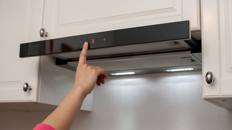 Person turning on the exhaust fan over the stove