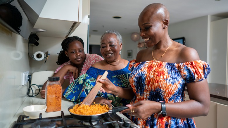 Three women cooking over a gas stove