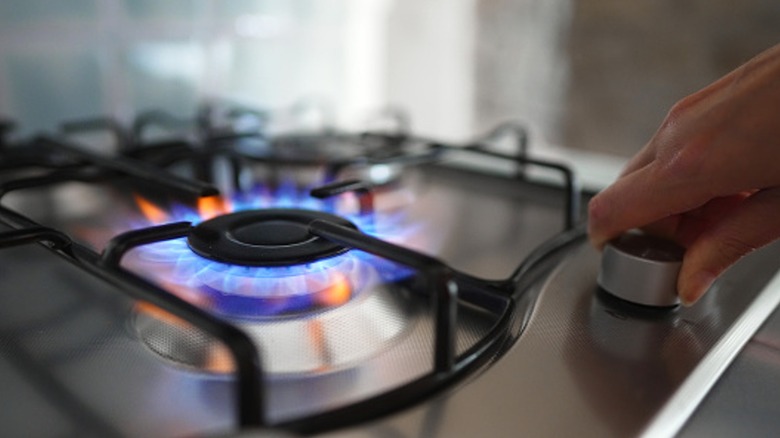 Person adjusting flame on gas stove