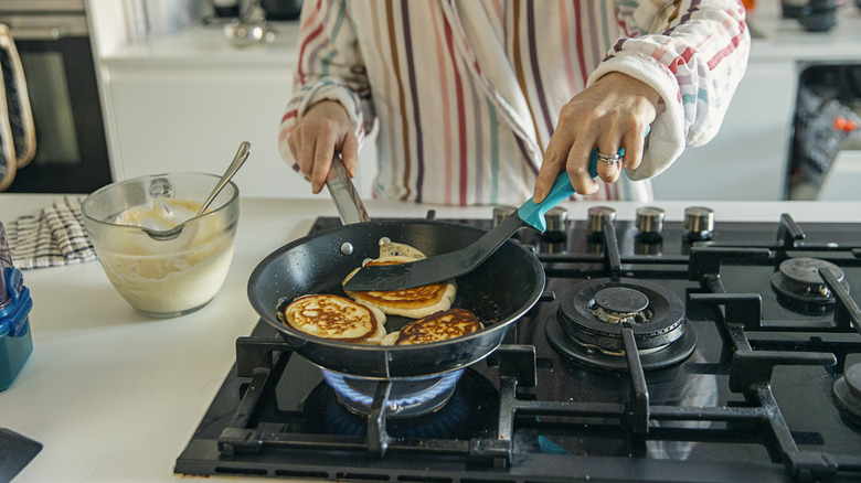 Person cooking pancakes on a gas stove