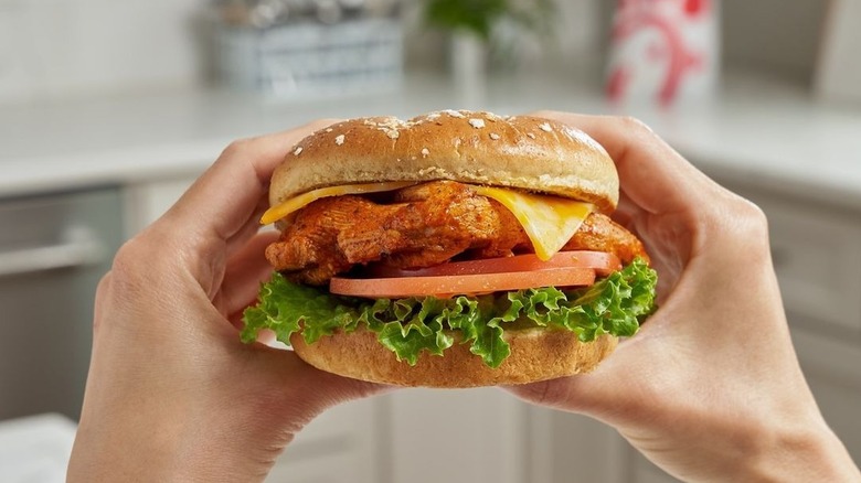 A pair of hands hold a Chick-fil-A Grilled Spicy Deluxe Sandwich.