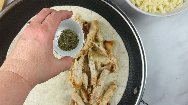 Hand sprinkling herbs onto chicken