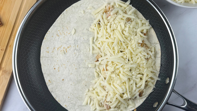 Quesadilla halfway filled with cheese in skillet