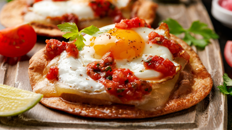 Huevos rancheros topped with tomato salsa, bean paste, and cheese.