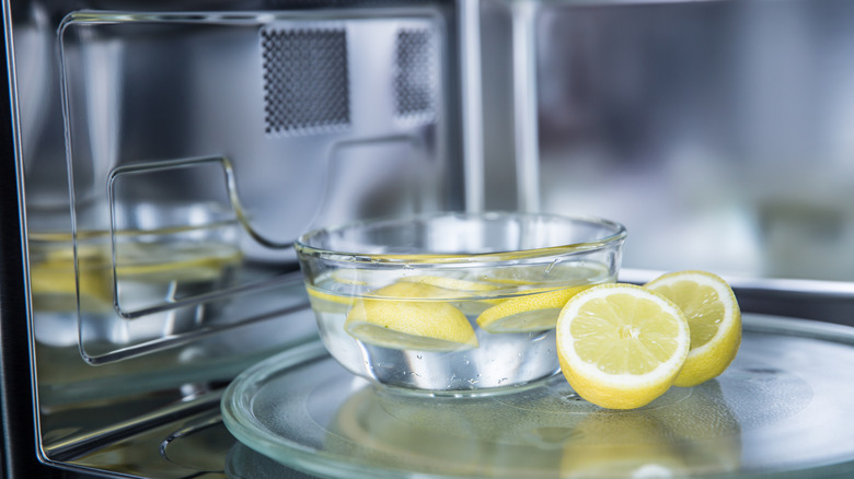 Sliced lemons and a bowl of lemon water in a microwave