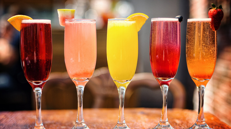 Five glasses of colorful cocktails with sparkling wine and fruit