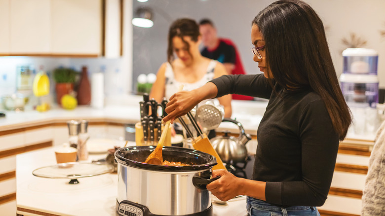 A woman mixing food in a slow cooker