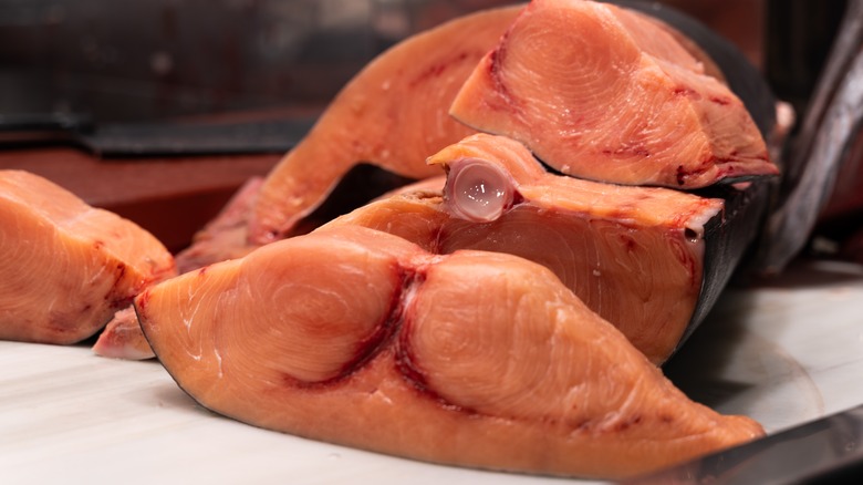 Close-up of fresh, large red swordfish slices displayed on a white board