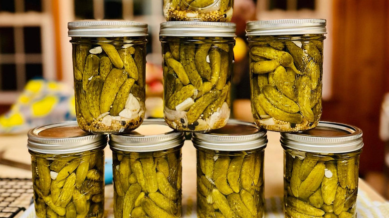 Stacked glass jars of pickles in brine and spices. 