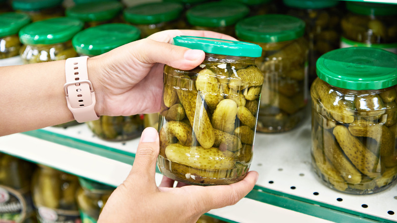 Person grabs pickle jar from shelf in grocery store
