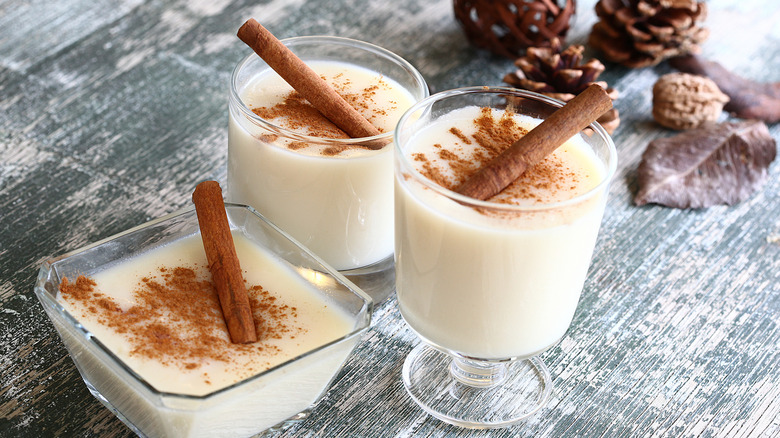 Eggnog with cinnamon in glass cups and bowl