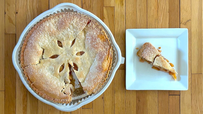 Whole and slice of Apple Pie on white square plate