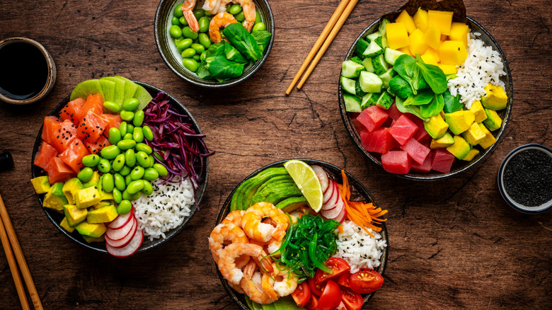 Poke bowls with tuna, salmon, shrimp, vegetables, legumes, avocado, and rice