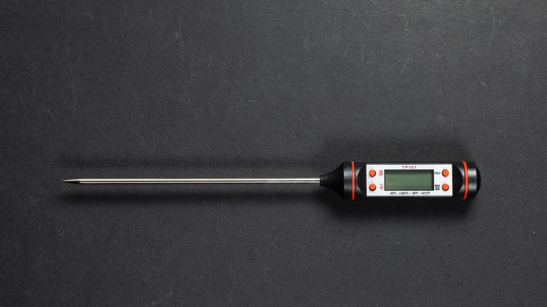 An image of a black and silver food thermometer isolated against a black background.