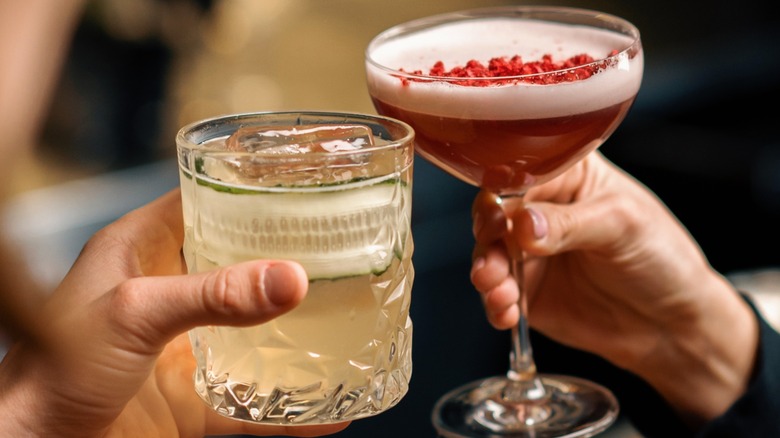 Two people cheering different cocktails