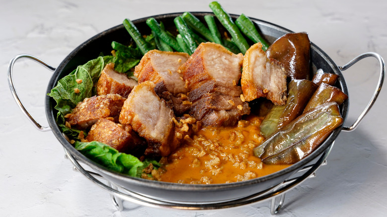 A silver bowl of kare-kare, a Philippine stew that features a thick savory peanut sauce and beef tripe