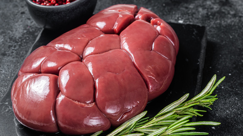 Beef veal kidney, raw offal meat on marble board with rosemary