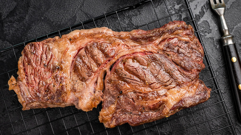 grilled chuck eye roll steak on a steel rack with fork